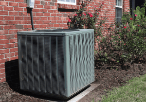 A green air conditioner sitting outside of a brick house.